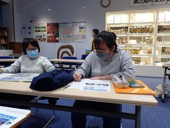 子どもたちが教室で資料を見ながら壁新聞を作成している様子の写真