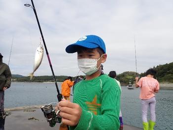 魚を釣り上げた釣り竿を持つ男の子の写真