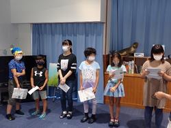 発表用の紙を持って前に並んでいる子どもたちの写真