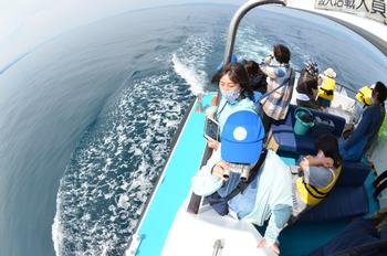 海の上を走る船の上で景色を見ている子どもたちの写真