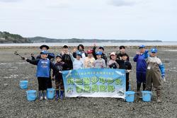 干潟で旗を持って記念撮影をしている子どもたちの写真