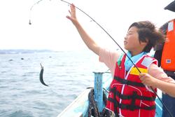 船の上で魚を釣り上げている子どもの写真
