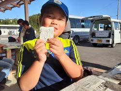 晴れた屋外で石こうで作った化石レプリカを笑顔でカメラに向かって見せている男の子の写真