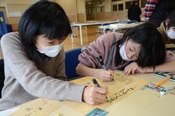 机に向かって真剣に壁新聞を製作している2人の女の子の写真
