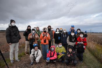 冬の草原で首に双眼鏡をさげた子どもたちが並んでいる集合写真