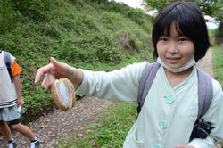 手にあけびのような形をした物を持ってカメラに見せている女の子の写真