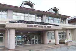 窓がたくさんあるピンクベージュの外壁と瓦屋根が特徴的な戸倉公民館の建物正面を捉えた写真