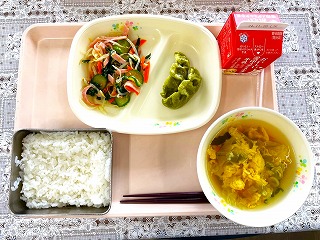 ピンクのトレーに給食が左から時計回りに牛乳、ケールともやしのナムル、仙台青葉ぎょうざ、卵とわかめのスープ、ごはんが並んでいる写真