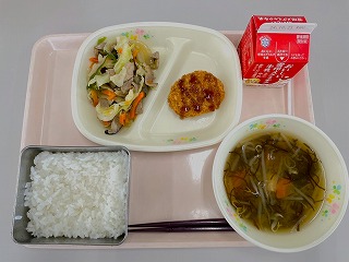 ピンクのトレーに給食が左から時計回りに野菜ソテー、まぐろカツ（パックソース）、牛乳 、もずくのみそ汁、ごはんと並んでいる写真