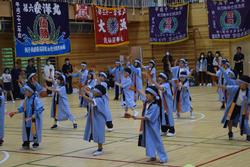 法被を着て鉢巻きを巻いた生徒たちが、観客が見守る中、リズムに合わせて踊りを披露している様子の写真