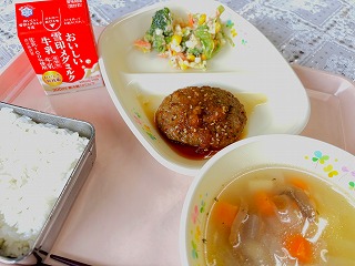 ピンクのトレーに給食が左から時計回りに牛乳、ブロッコリーとツナの梅マヨサラダ、和風おろしハンバーグ、コンソメスープ、ごはんと並んでいる写真