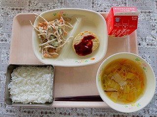 ピンクのトレーに給食が左から時計回りにごぼうサラダ、とうふハンバーグ、牛乳、白菜スープ、ごはんが並んでいる写真