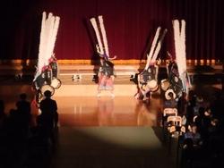 体育館の舞台前で、衣装を身に着けた生徒たちが、伝統芸能「水戸辺鹿躍」を披露している様子の写真