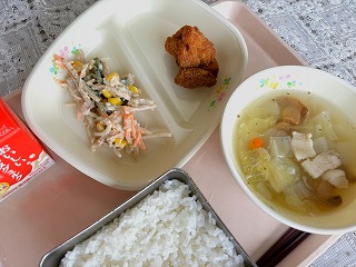 ピンクのトレーに給食が左から時計回りに牛乳、ごぼうサラダ、鶏肉のから揚げ、ベーコンと玉ねぎのスープ、ごはんと並んでいる写真