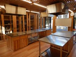 木製のキャビネットとステンレス製の調理台が並んでいる調理実習室の写真