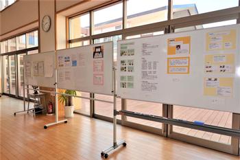 大きな窓から光が差し込む広い廊下に、子どもたちの活動や学習内容を紹介するカラフルな掲示物が貼られている写真