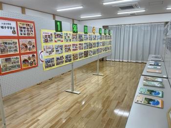 室内の中央にパネルが展示され、反対側には長机が設置されて展示品が並べられている写真
