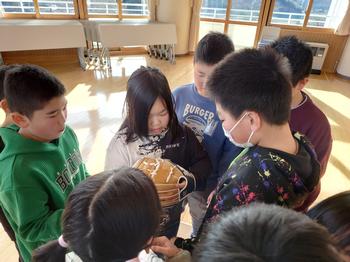 一人の女の子がグローブを手にはめて周りでほかの児童がみている写真