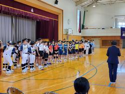 野球やバレーボールなど様々なユニフォーム姿の各部活動の選手たちが体育館のステージ前に横一列に並び、中総体壮行会がおこなわれている様子の写真