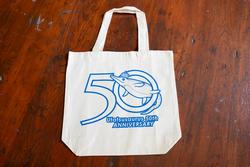 ベージュ色の布製エコバッグの前面に、イルカのイラストとともに『Ushuaiaaurus 50th ANNIVERSARY』と書かれた青いデザインが描かれているオリジナルグッズのエコバックの写真