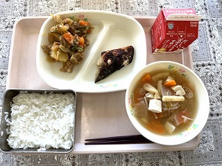 ピンクのトレーに給食が左から時計回りに肉じゃが、さばの塩麹焼き、牛乳、えのきと油あげのみそ汁、ごはんと並んでいる写真