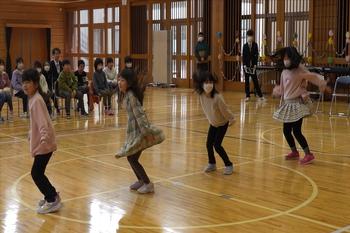 体育館の中央で一列に並んだ4人の女の子たちが、スカートをなびかせてリズムに合わせて元気いっぱいダンスを披露している写真