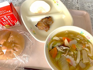 ピンクのトレーに給食が左から時計回りに牛乳、蔵王のなし、鶏肉のマーマレード焼き、ちゃんぽんうどん、ミルクパンと並んでいる写真