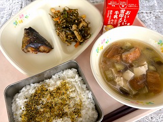 ピンクのトレーに給食が左から時計回りにあじのレモンソースかけ、すき昆布の煮物、牛乳、油ふとなすのみそ汁、ふりかけごはんと並んでいる写真