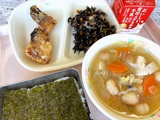 ピンクのトレーに給食が左から時計回りに南三陸産さばのからあげ、ひじきと大豆の煮物、牛乳、キャベツの味噌汁、味つけのりがのったごはんと並んでいる写真