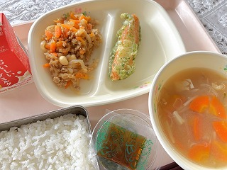 ピンクのトレーに給食が左から時計回りに牛乳、大根のきんぴら、笹かまの磯部揚げ、えのきだけのみそ汁、めかぶとろろ、ごはんが並んでいる写真