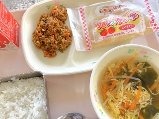 ピンクのトレーに給食が左から時計回りに牛乳、ドライカレー、セレクトデザート、わかめと玉子のスープ、ごはんが並んでいる写真