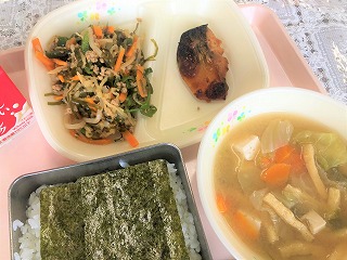 ピンクのトレーに給食が左から時計回りに牛乳、切干大根と昆布の煮物、さばのキムチ焼き、しめじと豆腐のみそ汁、味付けのりが置かれたごはんと並んでいる写真