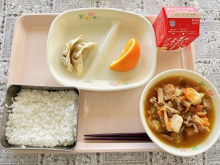 ピンクのトレーに給食が左から時計回りに青しそぎょうざ（2こ）、カットされたいよかん、牛乳、すきやき煮、ごはんが並んでいる写真