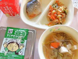 ピンクのトレーに給食が左から時計回りに牛乳、さばの味噌マヨ焼き、大根のきんぴら、もずくのみそ汁、ふりかけ、ごはんが並んでいる写真