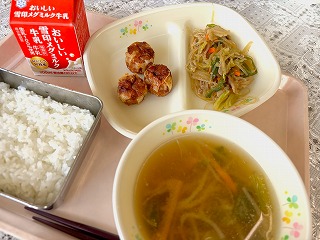 ピンクのトレーに給食が左から時計回りに牛乳、揚げしゅうまい、野菜たっぷりチャプチェ、もやしとコーンのみそスープ、ごはんと並んでいる写真