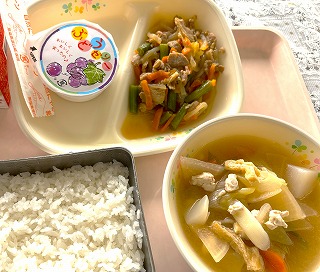 ピンクのトレーに給食が左から時計回りに牛乳、ぶどうゼリー、豚丼の具、けんちん汁（みそ味）、ごはんと並んでいる写真