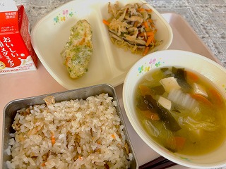 ピンクのトレーに給食が左から時計回りに牛乳、 笹かまの磯部上げ、切り干し大根ともやしの煮物、わかめと豆腐のみそ汁、 まいたけごはんと並んでいる写真