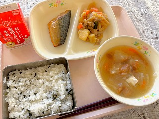 ピンクのトレーに給食が左から時計回りに牛乳、さばの照り焼き、肉じゃが、油ふのみそ汁、わかめごはんが並んでいる写真