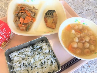 ピンクのトレーに給食が左から時計回りに牛乳、れんこんきんぴら、さばのスタミナ焼き、麩のみそ汁、わかめごはんと並んでいる写真