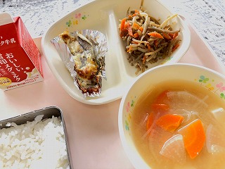 ピンクのトレーに給食が左から時計回りに牛乳、たらのタルタルソース焼き、きんぴらごぼう、大根と油あげのみそ汁、ごはんが並んでいる写真