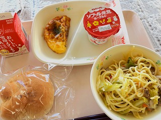 ピンクのトレーに給食が左から時計回りに牛乳、オムレツソースかけ、ヨーグルト、和風きのこスパゲティー、ミルクパンが並んでいる写真