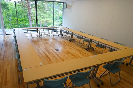 壁一面が窓になっている明るい会議室にロの字型に並べられた長机に20人程が座れる会議研修室1の写真