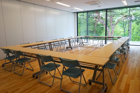 大きな窓の明るい室内にはロの字型に並べられた20人程が座れる会議研修室2の写真