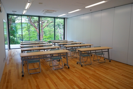 大きな窓の明るい室内に2人座れる長机10脚が2列に設置されている会議研修室3の写真