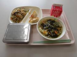 ピンクのトレイにご飯、ぎょうざ（2個）、豚肉と春雨のチャプチェ、わかめのスープ、牛乳が並んだ給食の写真