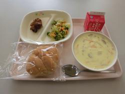 ピンクのトレイにパン、タンドリーチキン、ブロッコリーのソテー、じゃがいもとコーンのポタージュ、牛乳が並んだ給食の写真