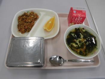 ピンクのトレイにご飯、大豆入りドライカレー、たまごとわかめのスープ、オレンジ、牛乳が並んだ給食の写真