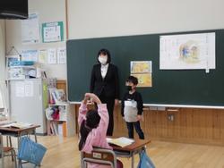 尾形亜樹先生と男子児童が黒板の前に立ち、女子生徒が自席に座り授業が行われている様子の写真