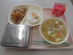 ピンクのトレイにご飯、ぶたどんの具、けんちん汁、豆乳プリン、牛乳が並んだ給食の写真