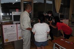 教室の窓際に集まりメダカを見ている男性と生徒3人の写真